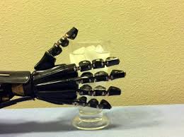 Robotic hand with artificial hand touching a glass of water with ice in it to test its temperature abilities