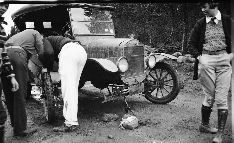 Woman watches as men change a tire on a Model T by simpleinsomnia is licensed under CC BY 2.0