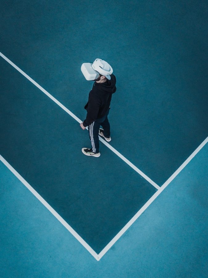 man+in+track+suit+wearing+VR+headset+standing+on+tennis+court