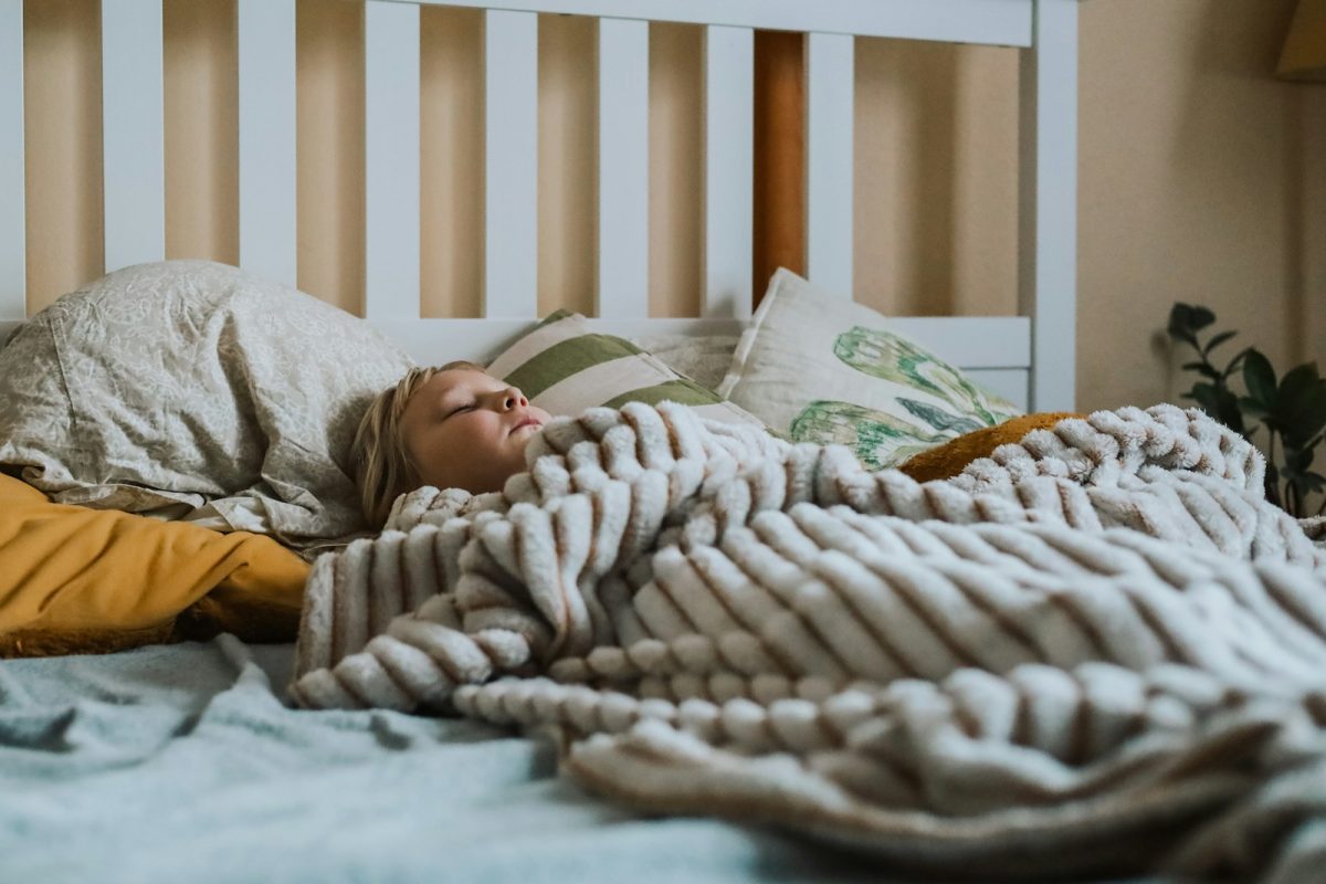 a small child sleeping under a blanket on a bed