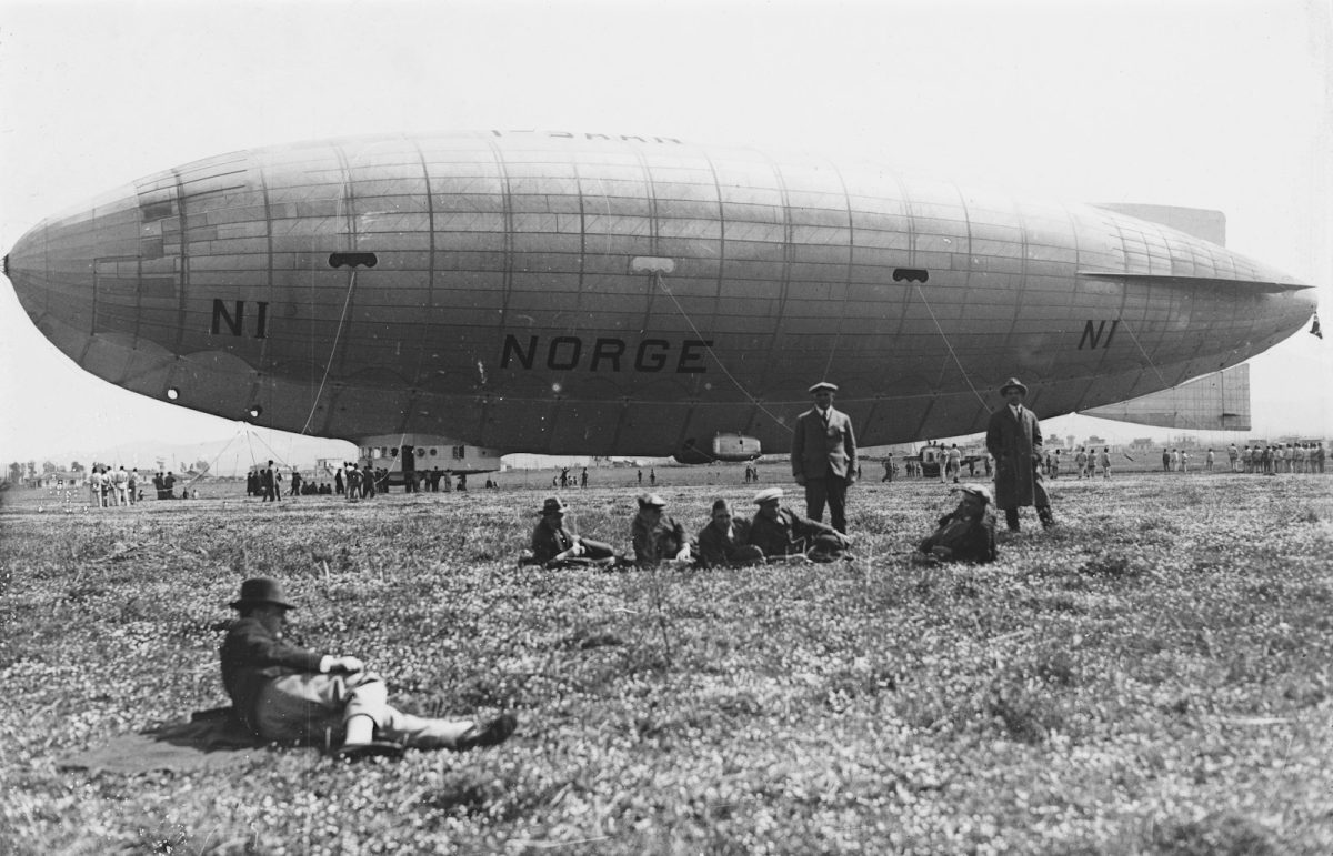 a group of people sitting on the ground in front of an airplane